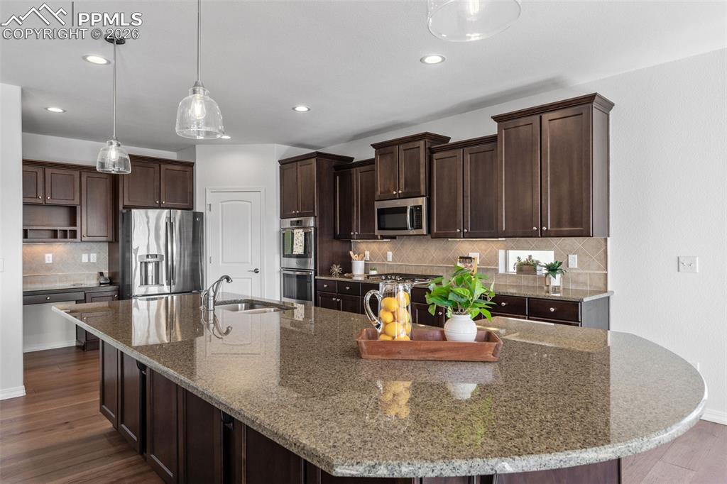Image 13 of 48: Kitchen featuring dark wood finish cabinetry, dark wood-type flooring, stai