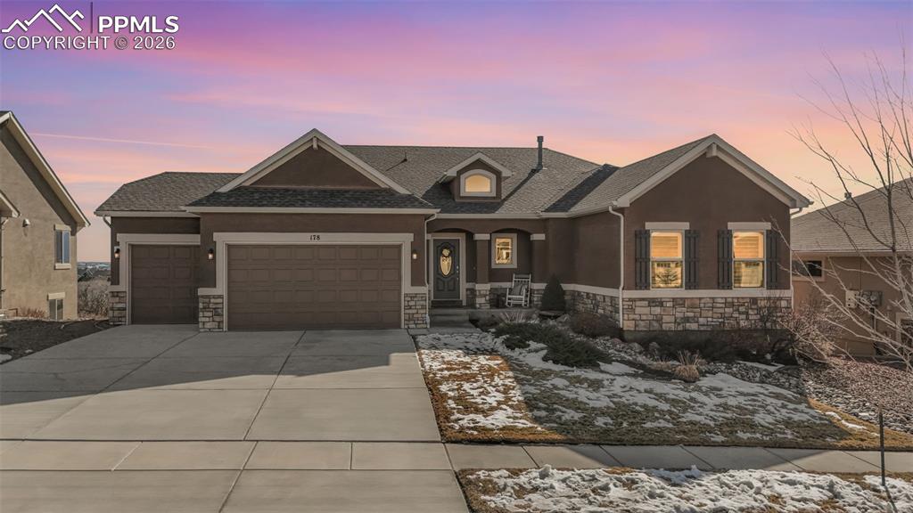 Image 2 of 48: View of front of property featuring a porch, stone siding, a garage, a shin