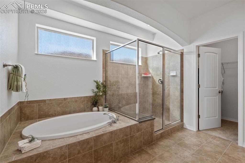 Image 23 of 48: Full bathroom with a garden tub, a walk in closet, a shower stall, and tile
