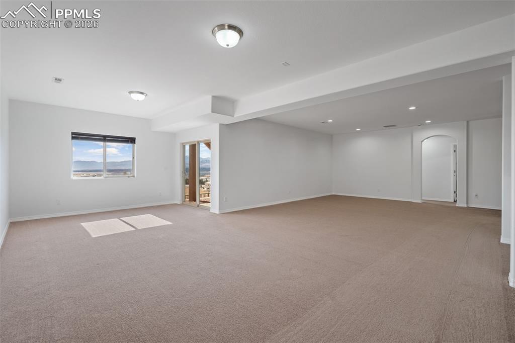 Image 29 of 48: Unfurnished room featuring light carpet, arched walkways, and recessed ligh