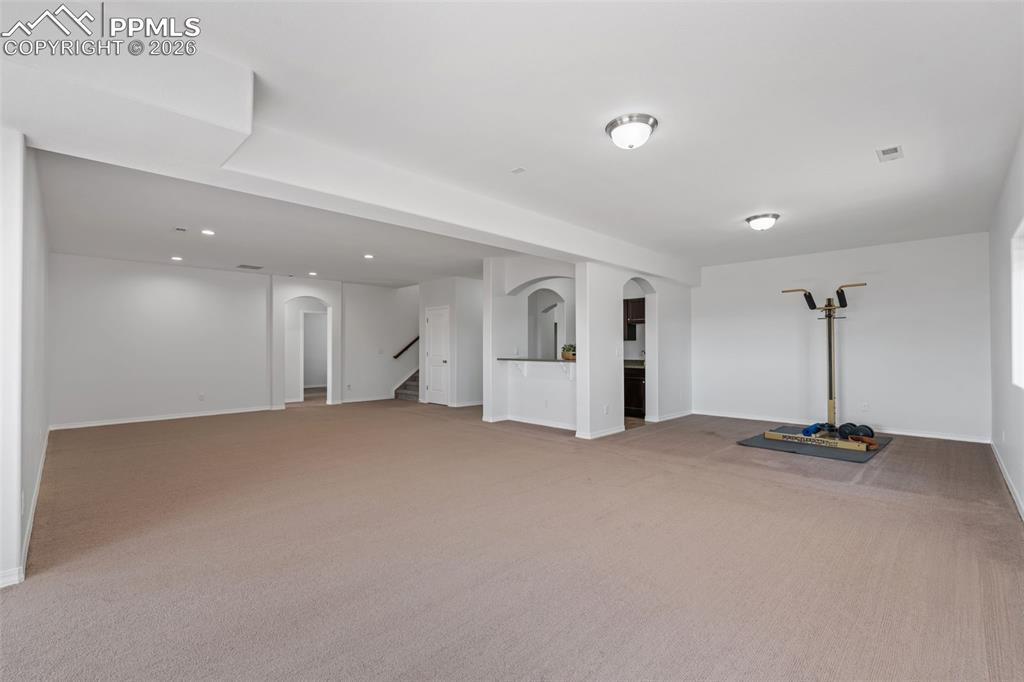 Image 31 of 48: Below grade area with arched walkways and light colored carpet