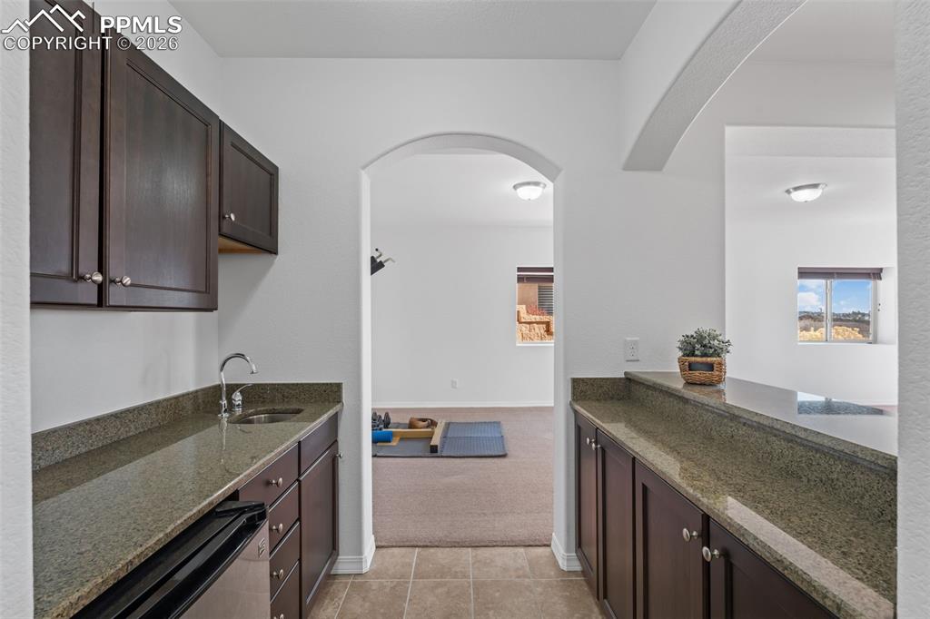 Image 33 of 48: Kitchen with dark wood finish cabinetry, dark stone countertops, and arched