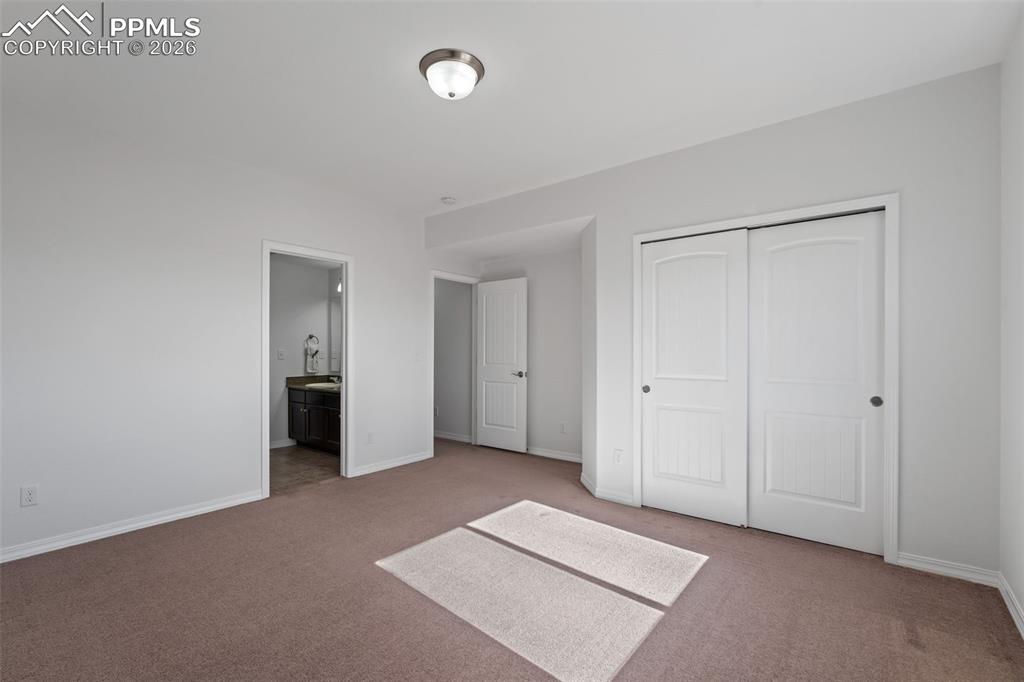 Image 38 of 48: Unfurnished bedroom with carpet flooring, ensuite bath, and a closet