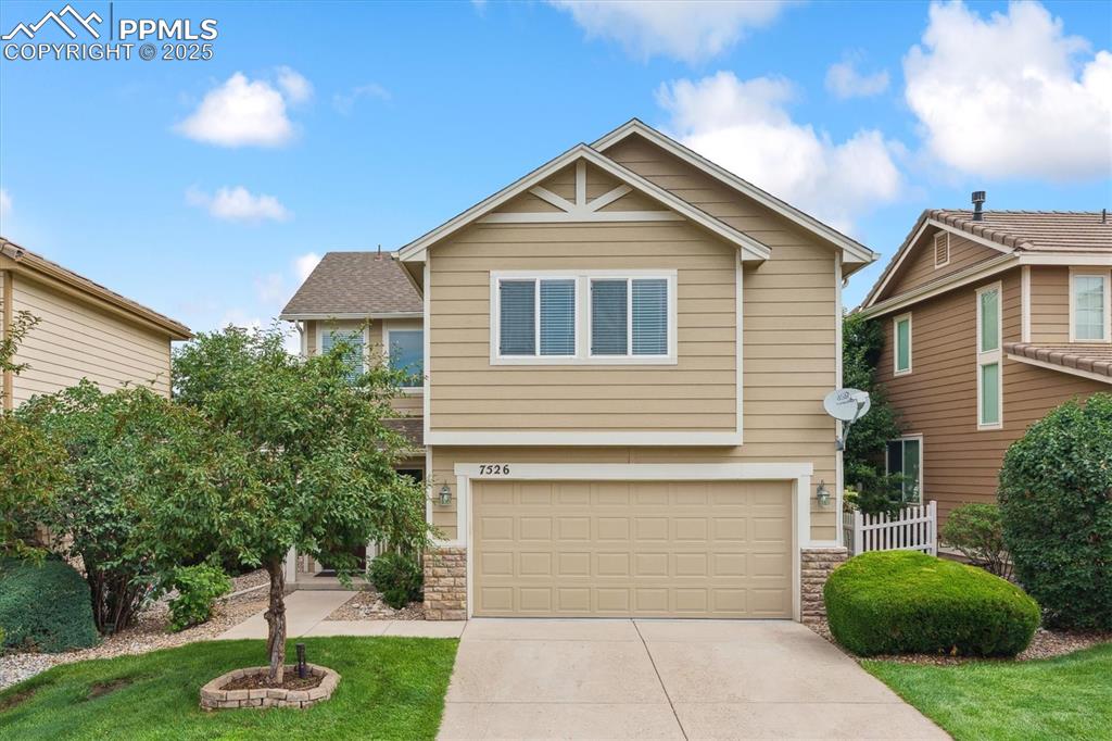 Caption: View of front of house featuring stone siding, concrete driveway, and an attached garage
