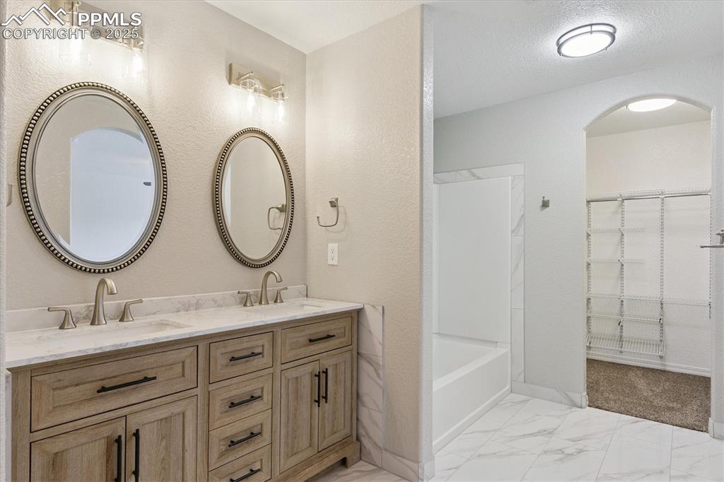Image 12 of 14: Bathroom featuring marble finish flooring, double vanity, and shower / wash