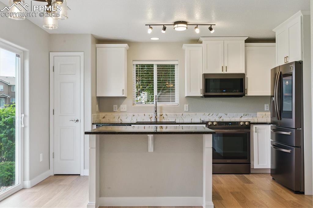 Image 5 of 14: Kitchen featuring appliances with stainless steel finishes, white cabinetry