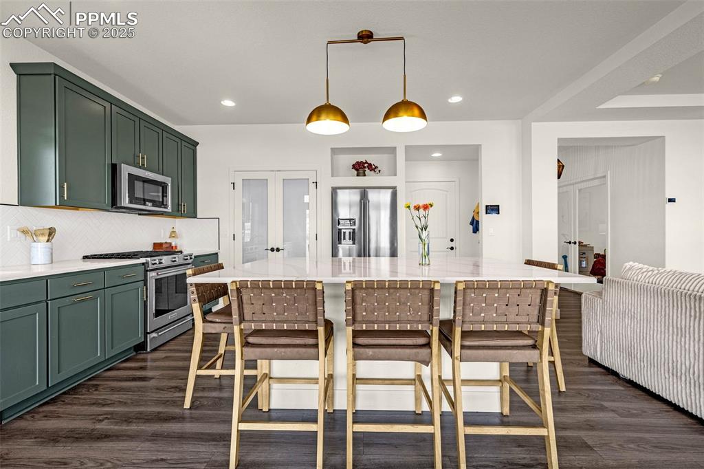 Image 10 of 32: Kitchen featuring green cabinetry, french doors, appliances with stainless