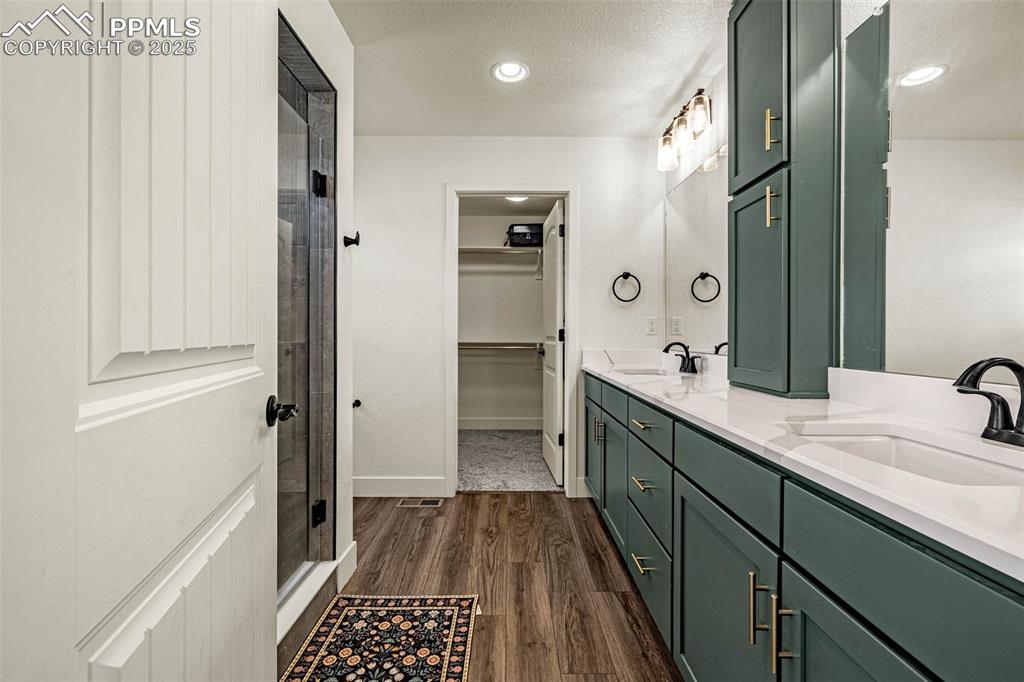 Image 16 of 32: Full bathroom with double vanity, a spacious closet, dark wood finished flo