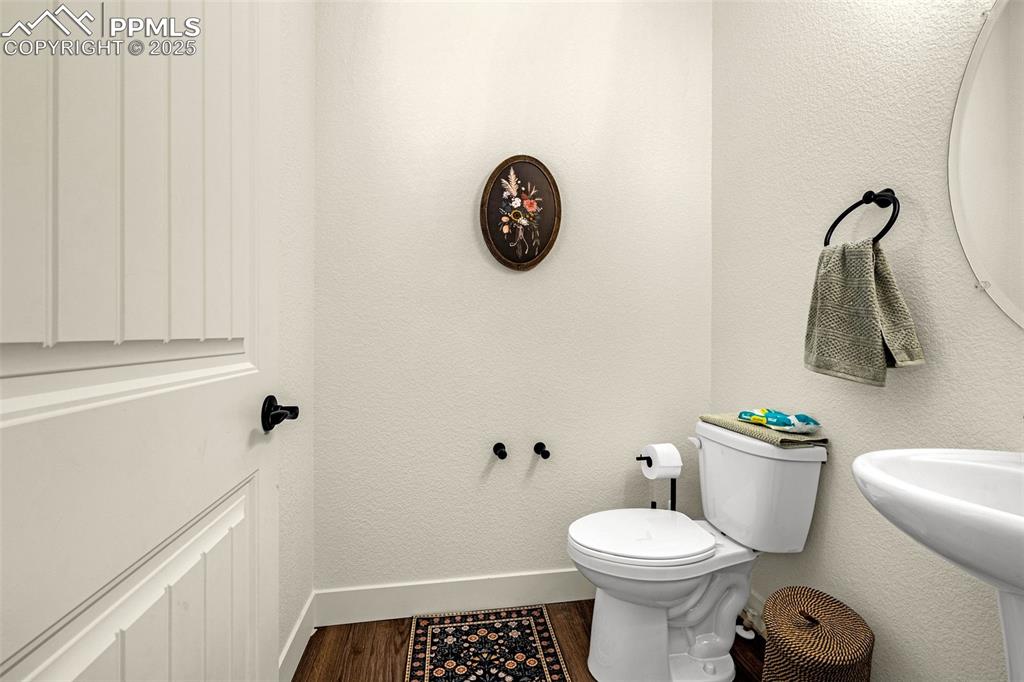 Image 20 of 32: Half bathroom with a textured wall and dark wood-type flooring