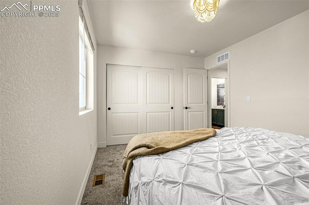 Image 21 of 32: Bedroom featuring carpet floors, a textured wall, and a closet