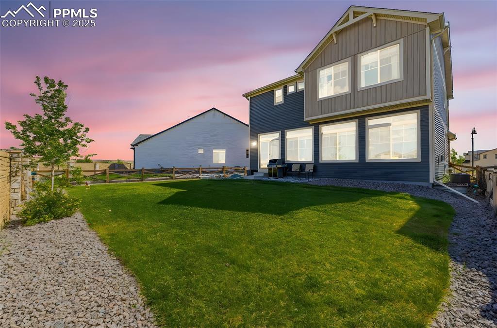 Image 27 of 32: Back of house at dusk featuring a fenced backyard, board and batten siding,