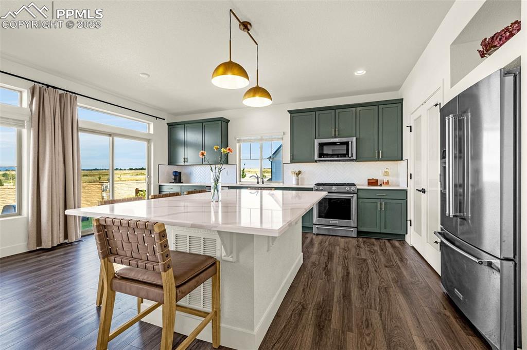 Image 3 of 32: Kitchen with green cabinets, appliances with stainless steel finishes, deco