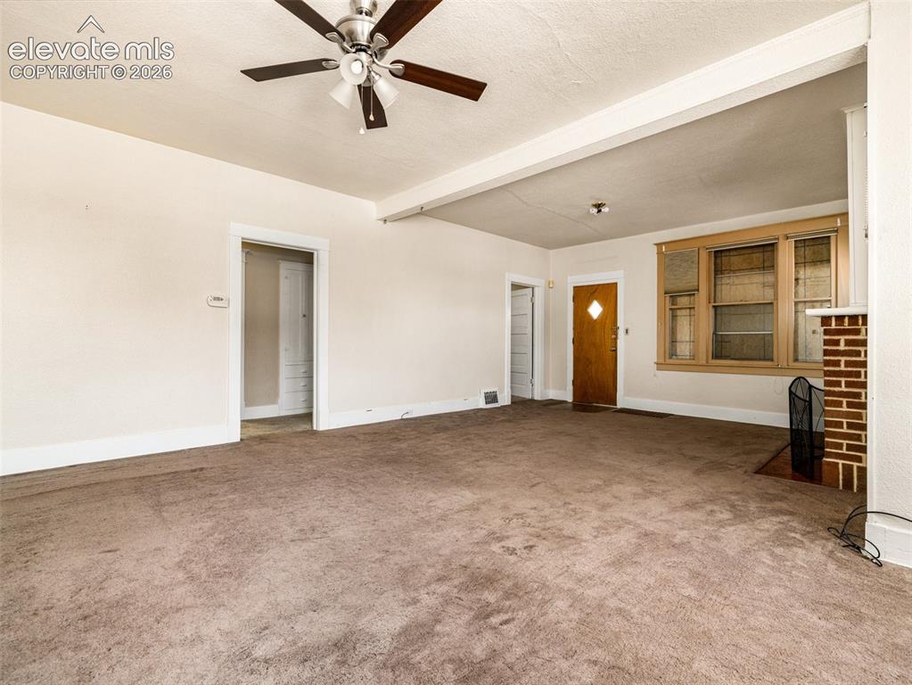 Image 5 of 22: Spacious room featuring ceiling fan, wood-frame windows, brick fireplace, a