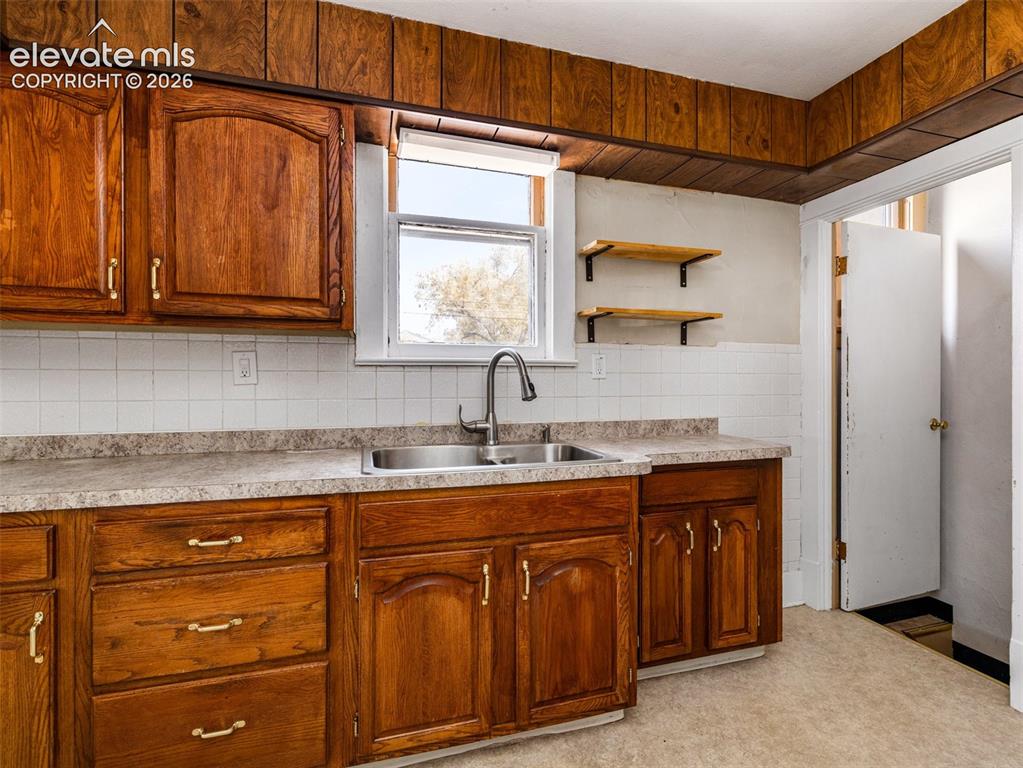 Image 7 of 22: Wood-finish cabinetry with brass-tone hardware, a dual-basin stainless stee