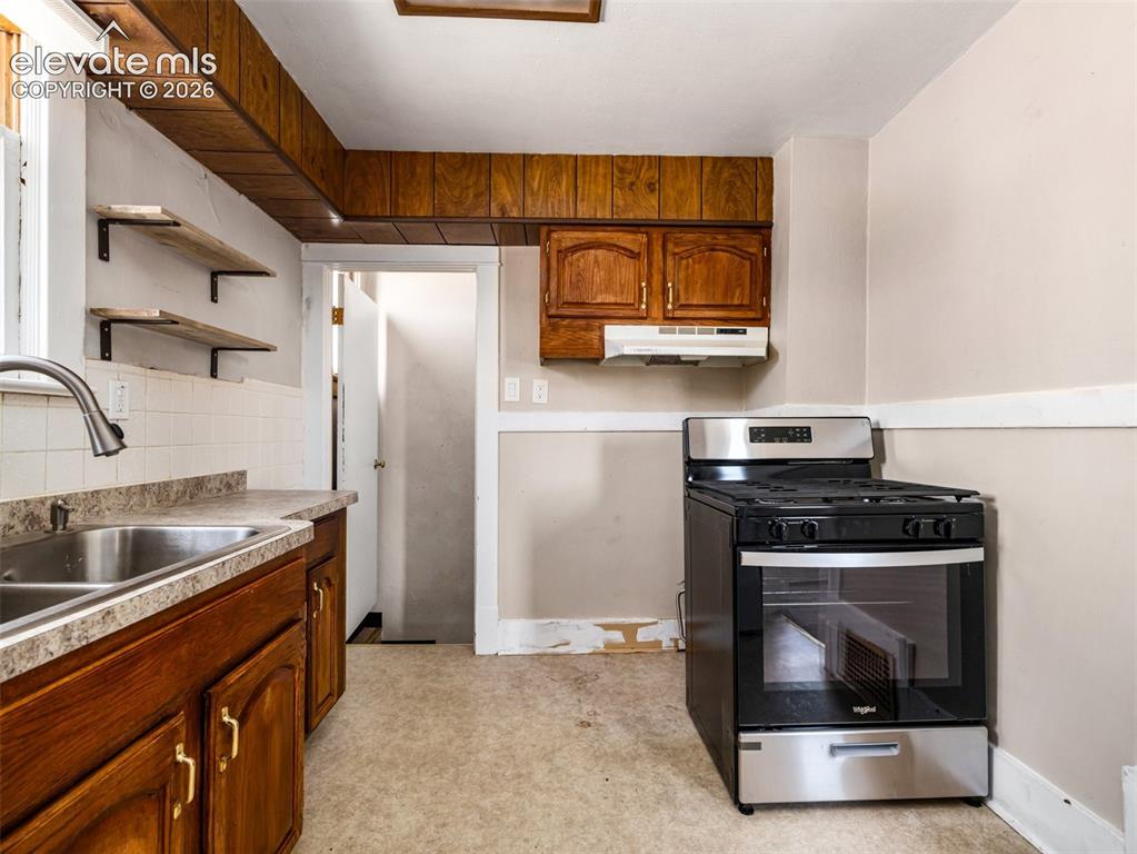 Image 8 of 22: Stainless steel range, wood cabinetry, tile backsplash, laminate countertop