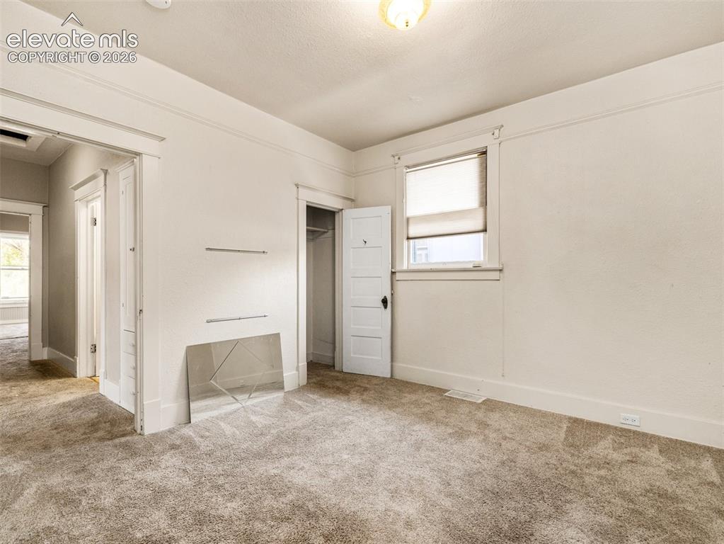 Image 9 of 22: Neutral-toned wall-to-wall carpeting, white painted walls, window with blin