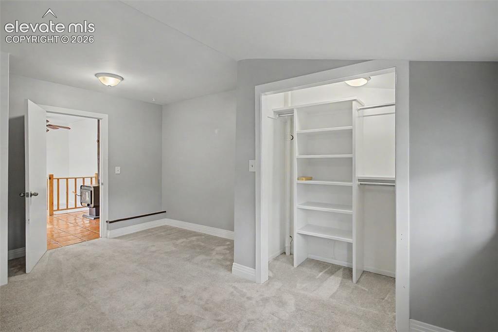 Image 14 of 27: Carpeted room featuring a built-in closet with shelving and hanging rods