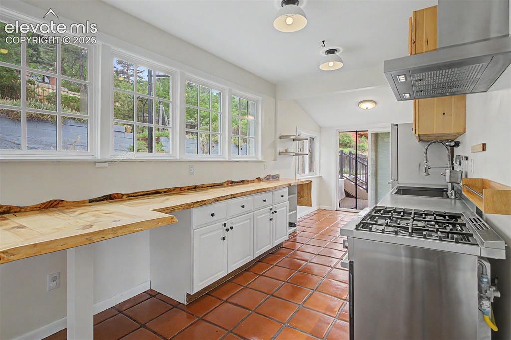 Image 7 of 27: Kitchen featuring terracotta tile flooring, white cabinetry, a stainless st
