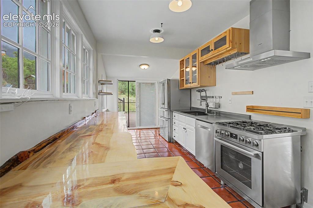 Image 8 of 27: Kitchen featuring a live-edge wood countertop, stainless steel appliances, 
