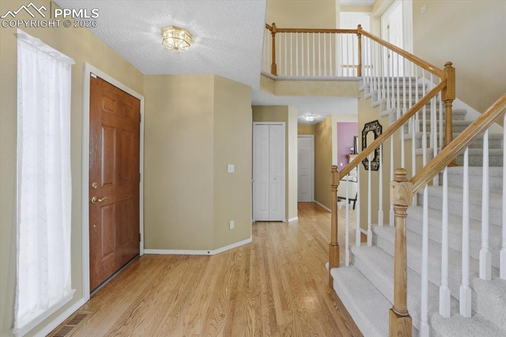 Image 6 of 48: Entry way with natural wood floors and sweeping stairs to the upper level.