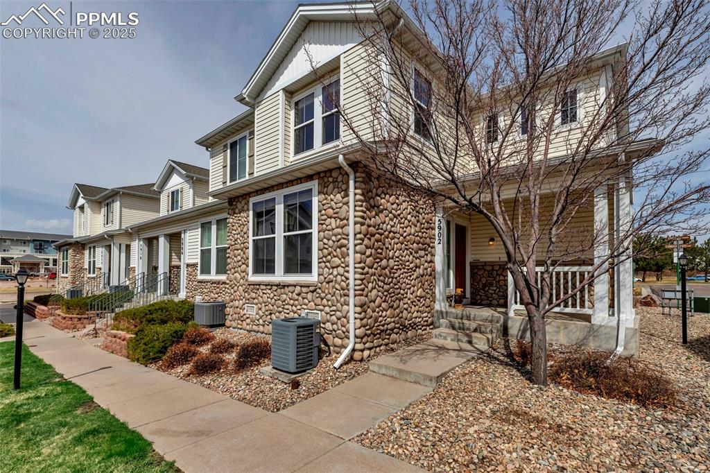Caption: View of front of house with a porch and stone siding
