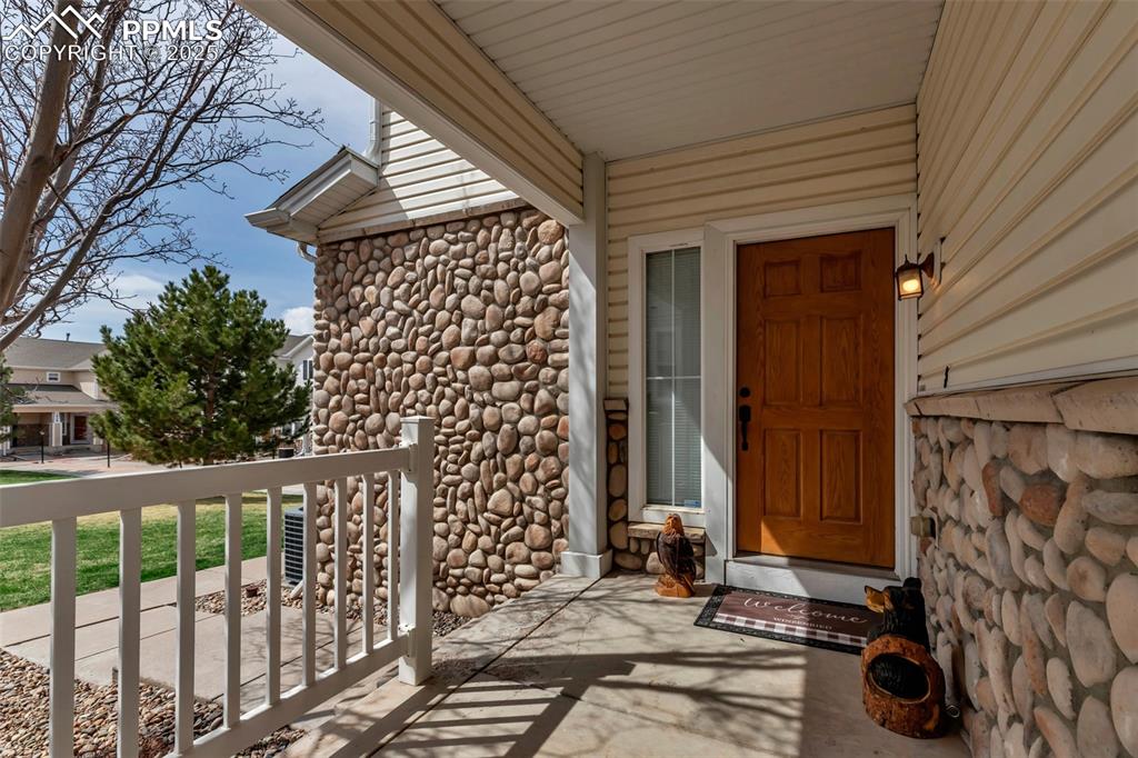 Image 10 of 46: Property entrance with stone siding and a porch