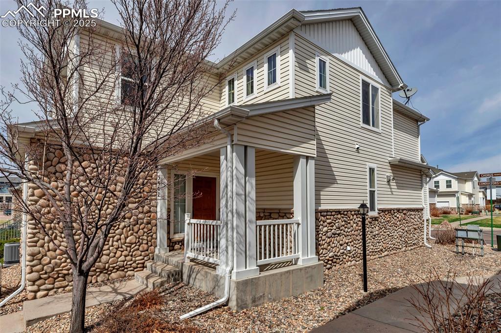 Image 11 of 46: View of property exterior with a porch and stone siding