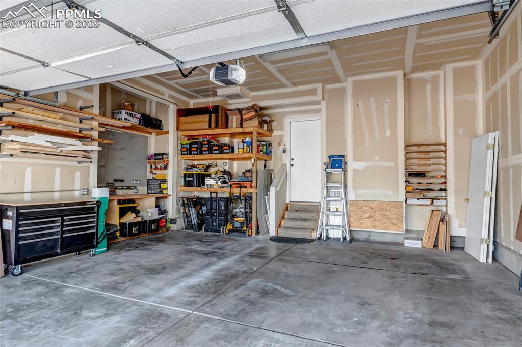Image 2 of 46: Garage with a workshop area and a garage door opener