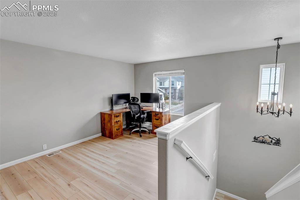 Image 20 of 46: Office space featuring light wood-style flooring and a chandelier