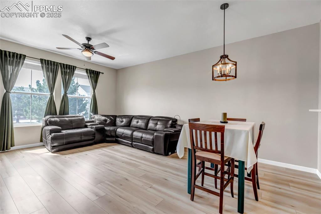Image 33 of 46: Living area with a ceiling fan, light wood finished floors, and a chandelie