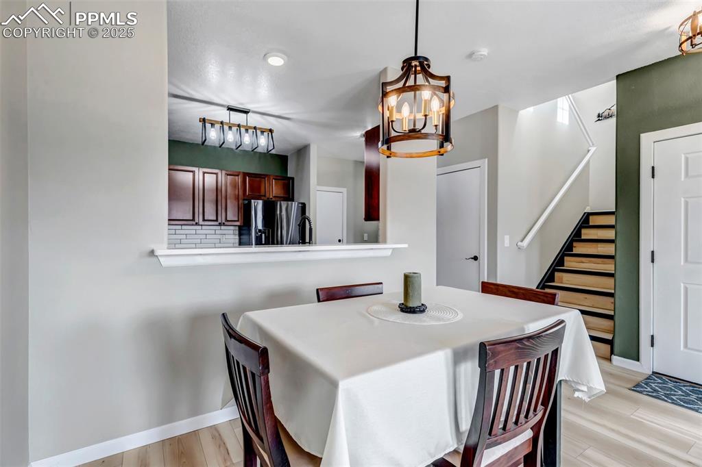 Image 36 of 46: Dining space with a chandelier, light wood-style flooring, and stairs