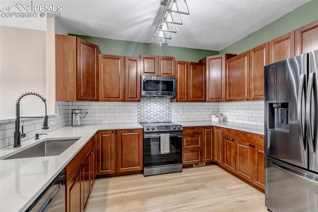 Image 37 of 46: Kitchen featuring stainless steel appliances, a textured ceiling, decorativ