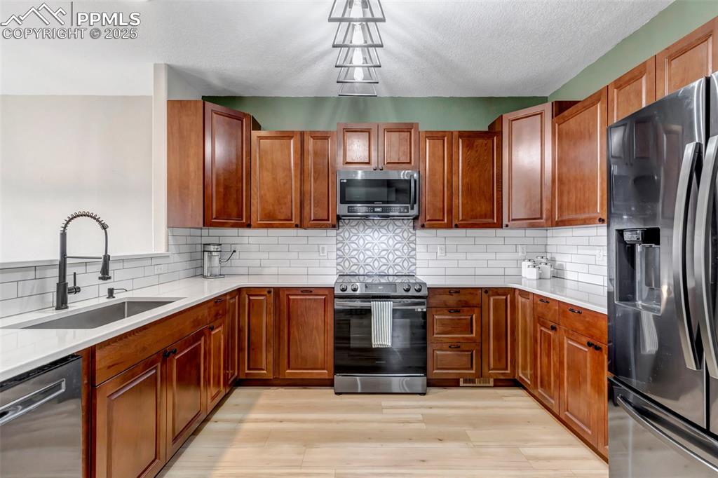 Image 38 of 46: Kitchen featuring stainless steel appliances, backsplash, light countertops