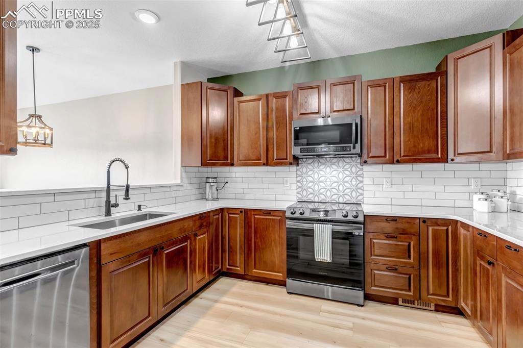 Image 39 of 46: Kitchen featuring stainless steel appliances, light wood-style floors, deco