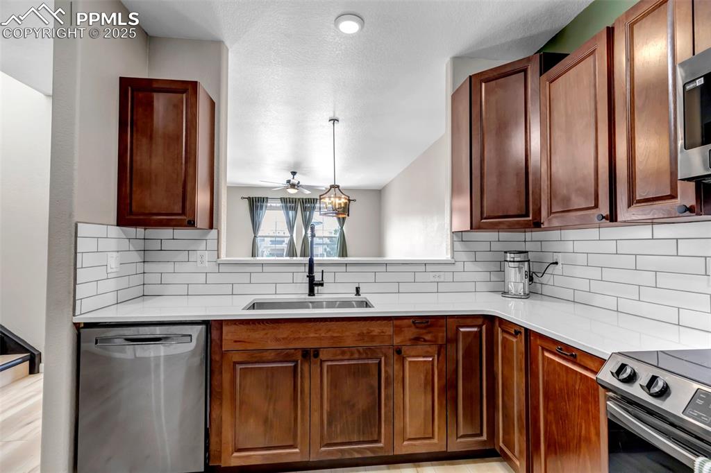 Image 40 of 46: Kitchen with backsplash, stainless steel appliances, a ceiling fan, light c