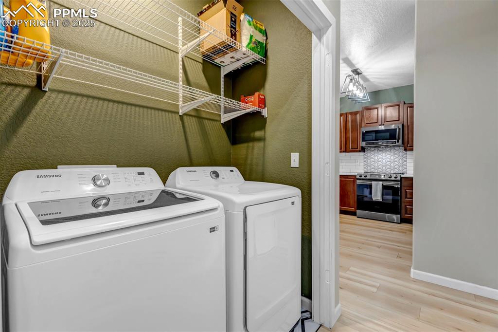 Image 41 of 46: Laundry room with independent washer and dryer, light wood-style floors, an