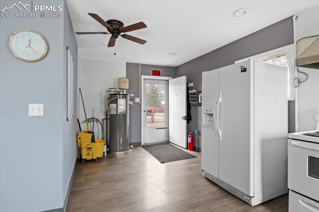Image 10 of 14: Kitchen with white appliances, wood finished floors, ceiling fan, and water