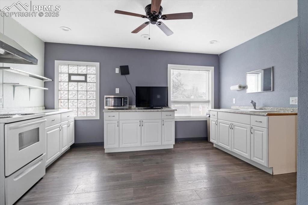 Image 9 of 14: Kitchen with white cabinets, stainless steel microwave, light countertops,