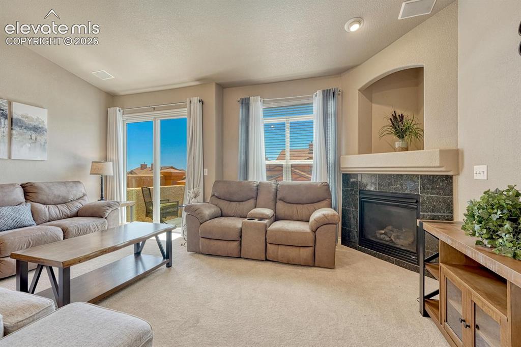 Image 12 of 41: Neutral-toned interior featuring a corner fireplace with a dark-tiled surro