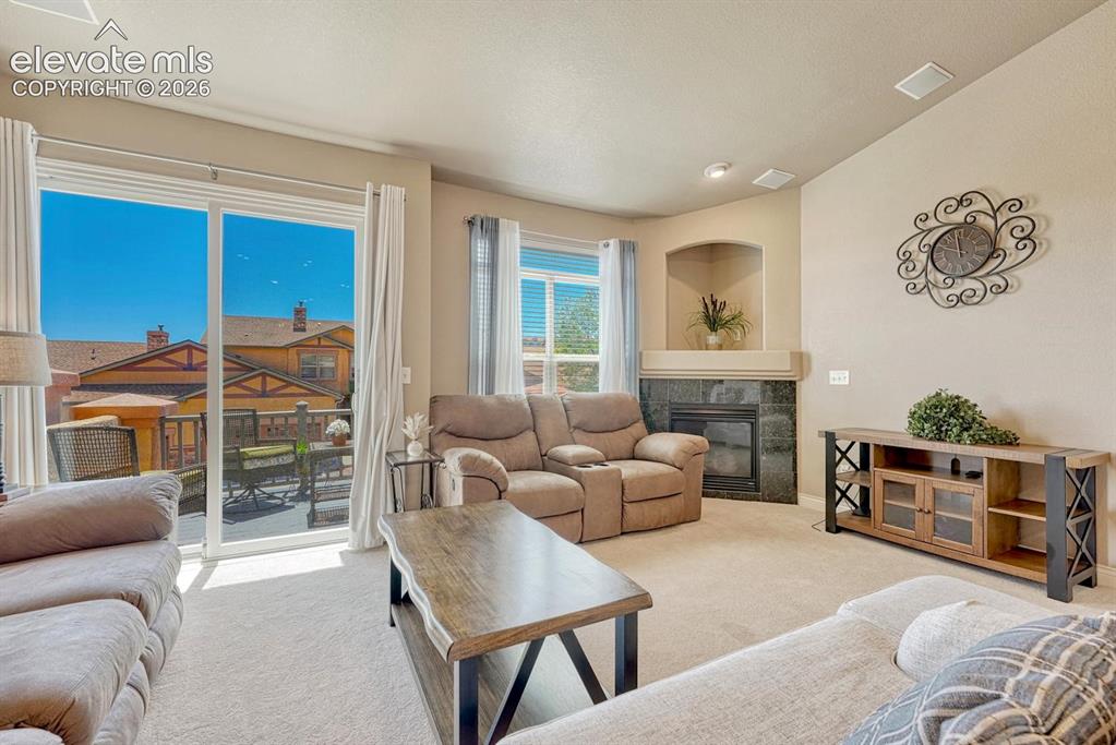 Image 16 of 41: Spacious living area featuring a built-in corner fireplace with dark stone