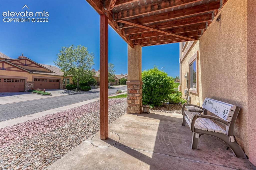 Image 41 of 41: Covered patio with a wood-beam ceiling, supported by a stone-faced column,