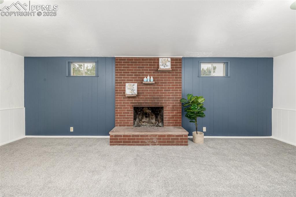 Image 13 of 36: Downstairs, find a cozy family room with wood burning fire place, fresh pai