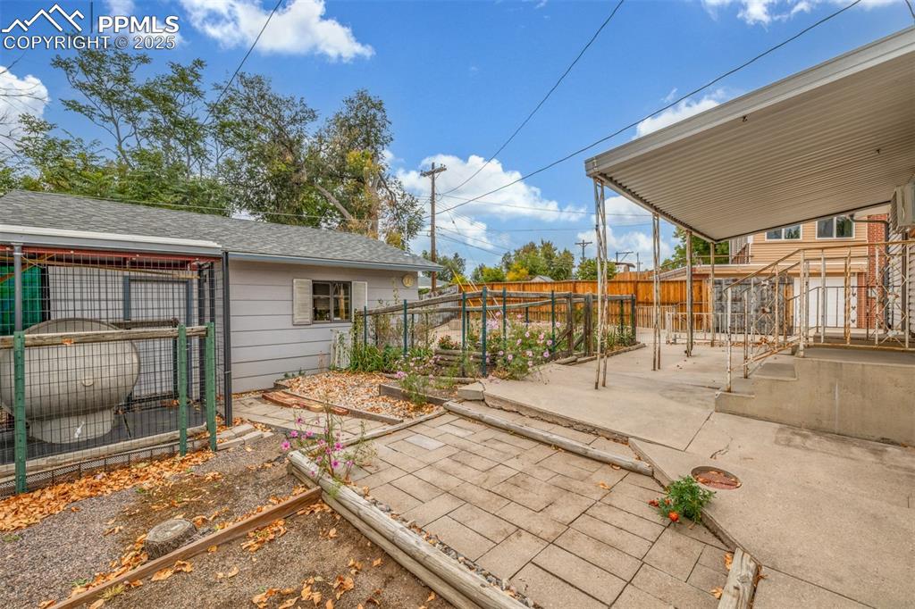 Image 25 of 36: Fenced backyard featuring a vegetable garden, a patio area, a dog kennell a