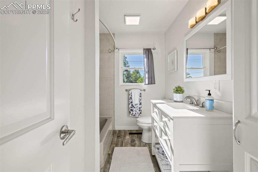 Image 17 of 39: Bathroom featuring vanity, bathtub / shower combination, and wood finished