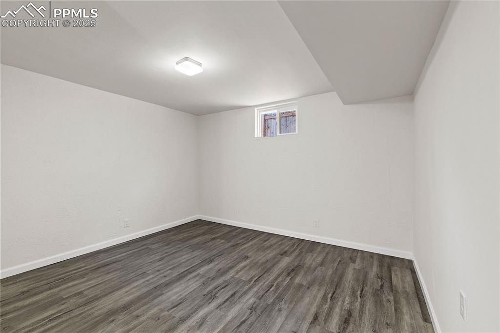 Image 23 of 39: Basement featuring dark wood-style flooring and baseboards
