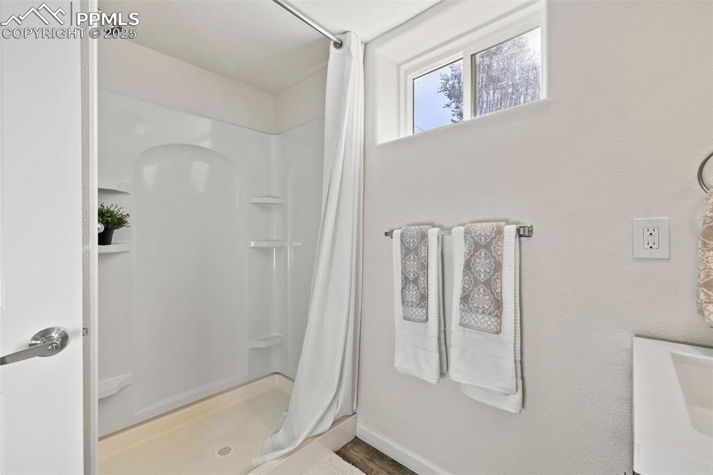 Image 30 of 39: Bathroom with curtained shower and baseboards