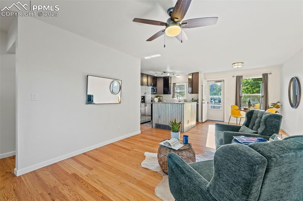 Image 7 of 39: Living room with light wood-style floors and a ceiling fan