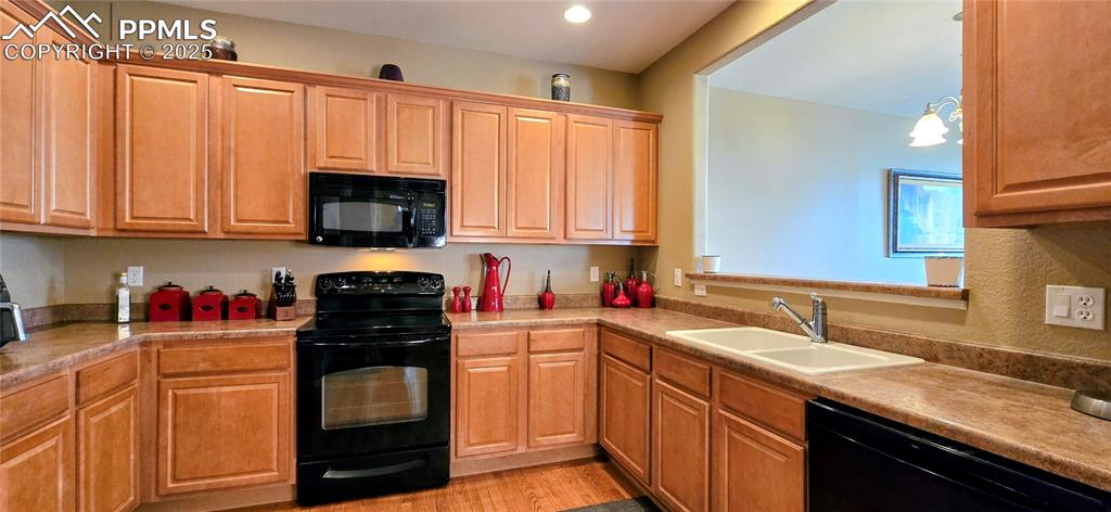 Image 10 of 37: Kitchen featuring black appliances, light wood-style flooring, pendant ligh