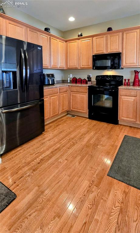 Image 11 of 37: Kitchen featuring black appliances, light wood-style floors, and recessed l