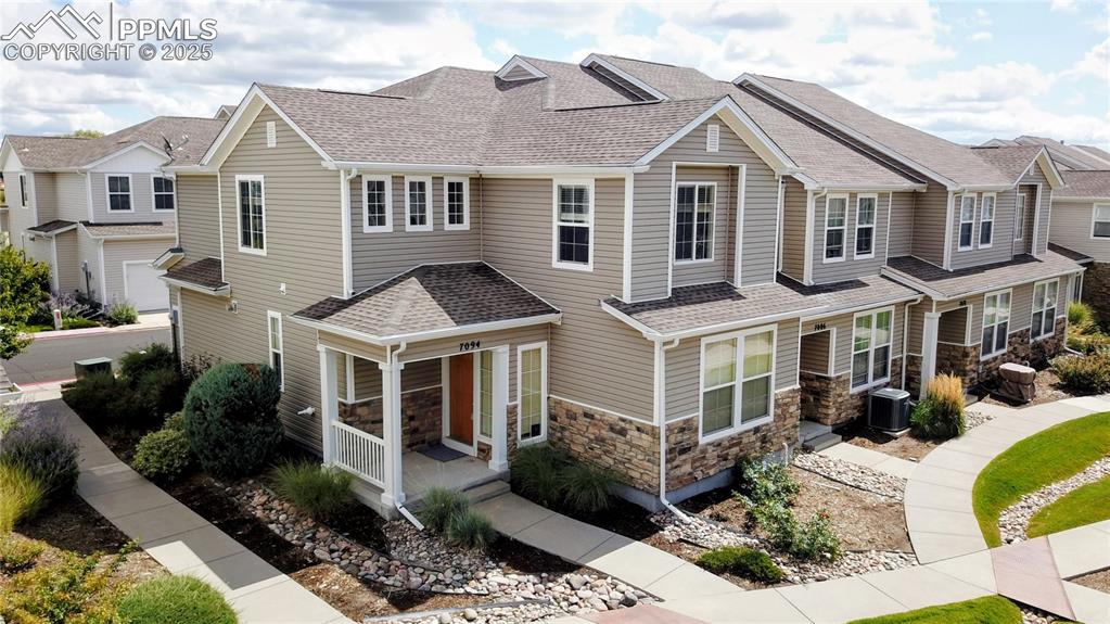 Image 34 of 37: Craftsman inspired home featuring a shingled roof, stone siding, and a resi